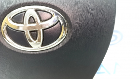 Airbag-ul lateral al șoferului din volanul unui Toyota Prius V 12-17 este negru și zgâriat.