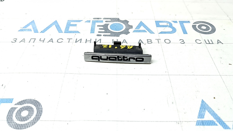 Emblema cu inscripția "quattro" de pe grila radiatorului Audi A6 C7 12-15 pre-restilizare