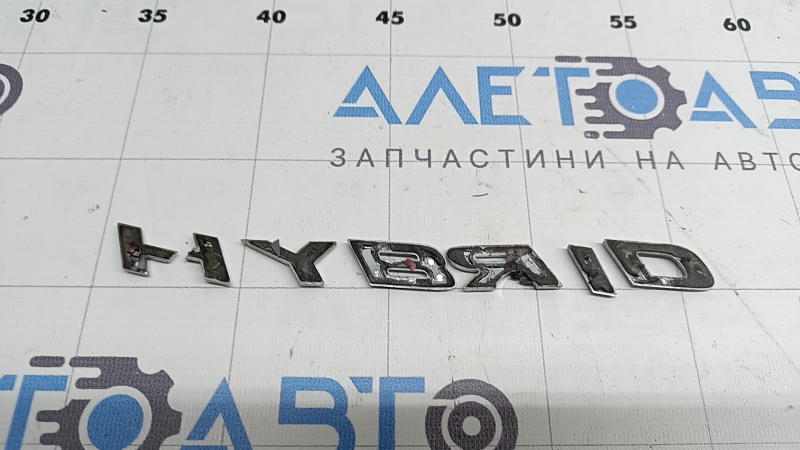 Emblema cu inscripția HYBRID de pe ușa spate dreapta a unui Lexus UX250h 19-22 este ruptă. Litera „H” este ruptă.
