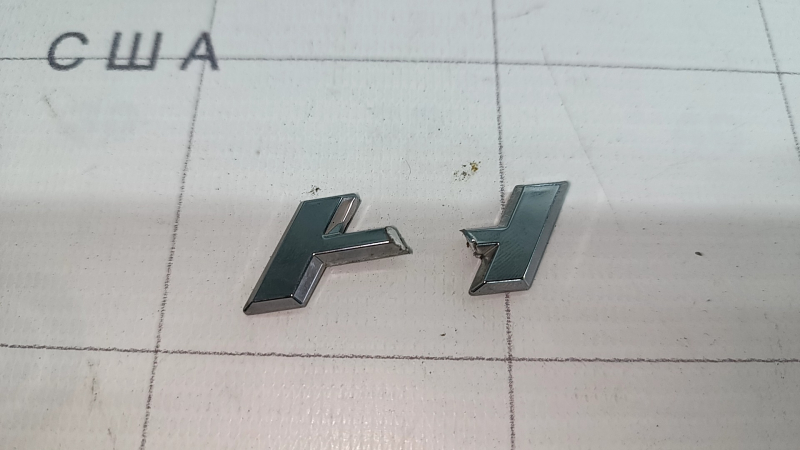 Emblema cu inscripția HYBRID de pe ușa spate dreapta a unui Lexus UX250h 19-22 este ruptă. Litera „H” este ruptă.
